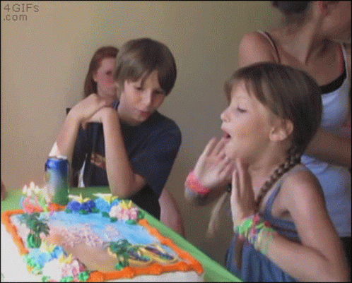 Vtipný narozeninový gif s dívkou, které žena, stojící za ní, ponoří obličej do narozeninového dortu.