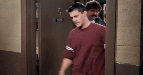 GIF. Joey from Friends walks away after Mr. Treeger slams the door in his face.