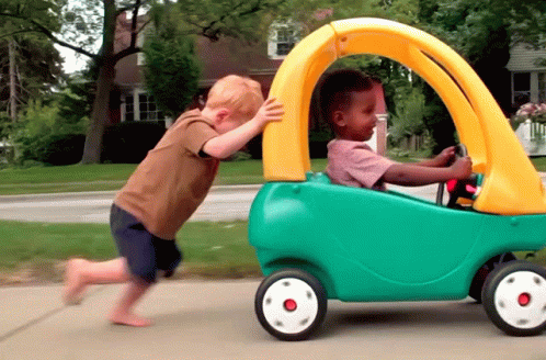 #PRATODOSVEREM: Duas crianças de até 4 anos estão brincando com um carrinho. Uma delas está dentro do carro e a outra empurrando pela calçada. 