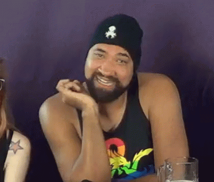 Bearded man in a beanie smiling and gesturing